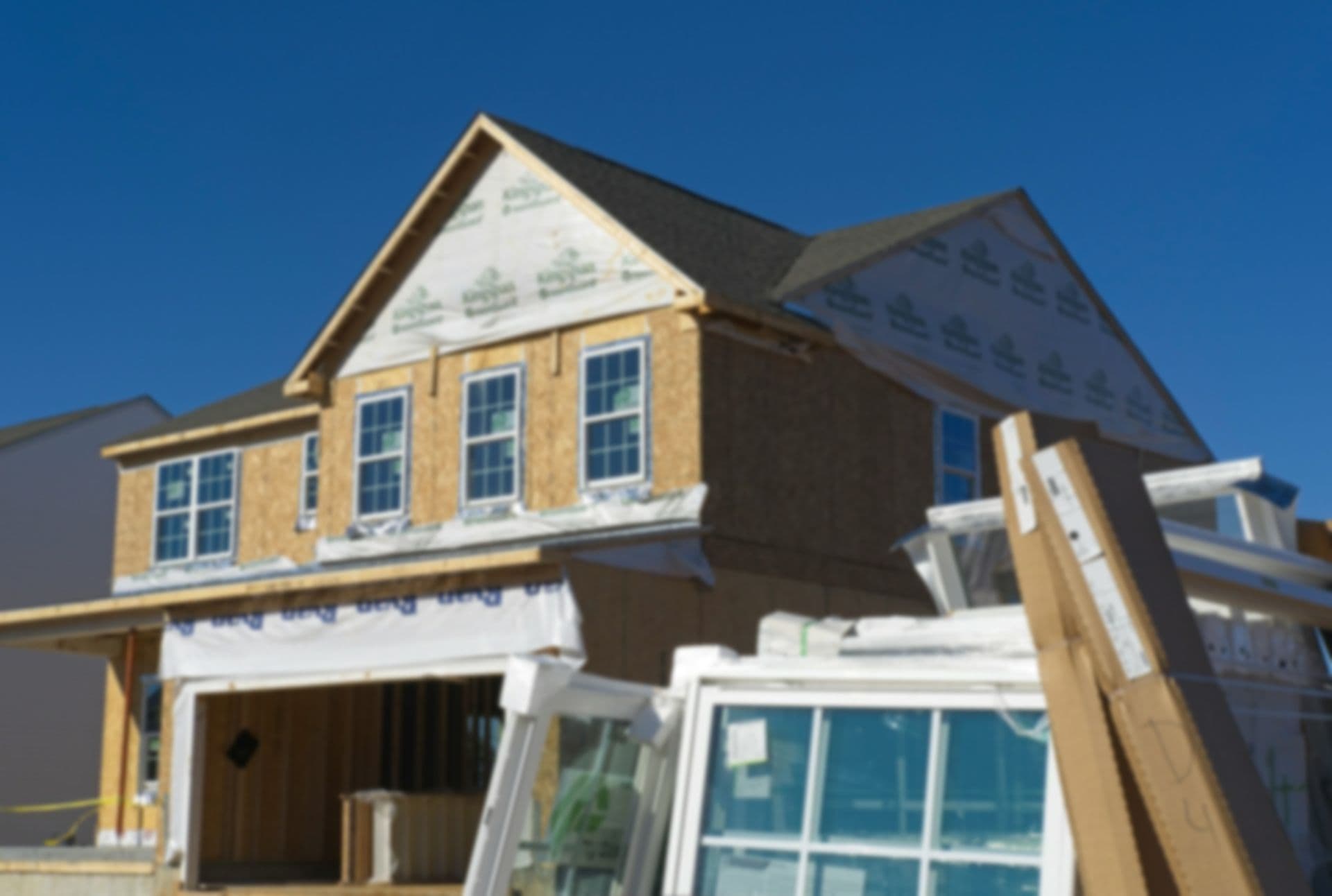 A new two-story house in build against a clear blue sky